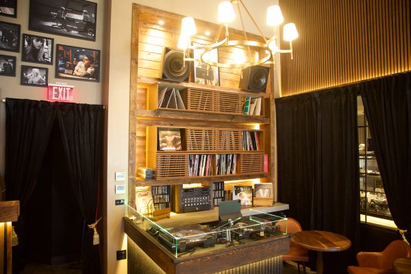 Two high tech turntables sit in front of racks of vinyl records. 